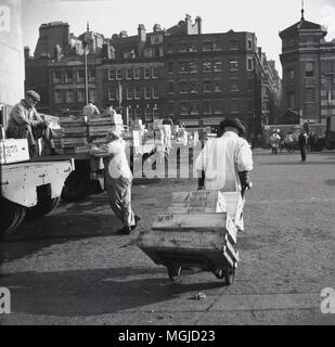 1950er Jahre, historische, Portier in der Londoner Billingsgate Fish Market ziehen einer Barrow von Kisten vom Lkw Park an der Themse. Stockfoto