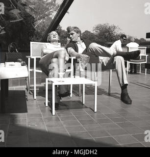 1960, historische, eine junge Paar sitzen, entspannen Sie bei einem Drink auf der Terrasse der Pavillion Cafe & Bar in der Serpentine am Hyde Park, London, England, UK. Stockfoto