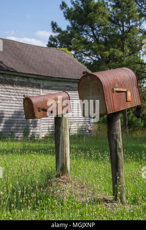 Verrostet Mailbox entlang einer Landstraße; gas Pumpe eine Erinnerung an vergangene Zeiten. Ländliche decay erzählt eine Geschichte inmitten der Rost, Vernachlässigung, und überwucherung. Stockfoto