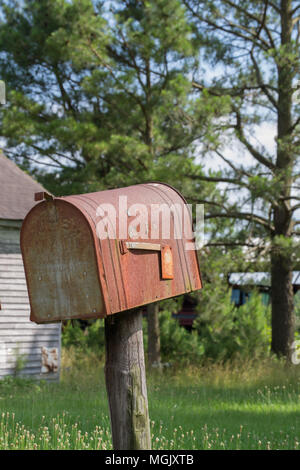 Verrostet Mailbox entlang einer Landstraße; gas Pumpe eine Erinnerung an vergangene Zeiten. Ländliche decay erzählt eine Geschichte inmitten der Rost, Vernachlässigung, und überwucherung. Stockfoto