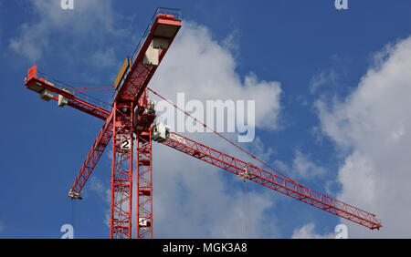 Zwei rote Krane vor einem strahlend blauen Himmel mit flauschigen weissen Wolken Stockfoto