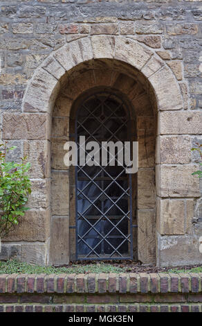 Alten schattigen Bereich Steinmauer mit grünen Pflanzen und vergitterten Fenster Stockfoto