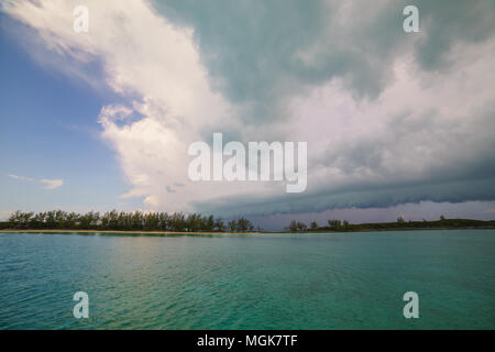 Tropischer Sturm wolken Ansatz über eine isolierte Insel mit ruhigem Wasser Stockfoto