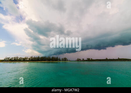 Tropischer Sturm wolken Ansatz über eine isolierte Insel mit ruhigem Wasser Stockfoto