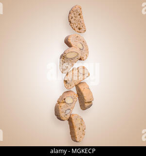 Italienische cantuccini Fliegen auf einem beigen Hintergrund Hintergrund. Der Stücke von Cookies. Surreale kreatives Konzept. Stockfoto