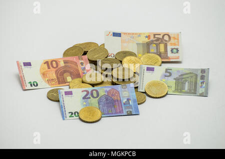 Ein Haufen von Münzen, die Europäische Währung EURO mit Miniatur Banknoten 5, 10, 20, 50 EURO. Auf weißem Hintergrund mit Freistellungspfad isoliert. Stockfoto