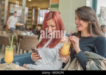 Porträt von zwei junge schöne Frauen über Handy im Coffee Shop. Zwei junge weibliche Freunde zusammen genießen Sie in einem Restaurant lachen, reden Stockfoto