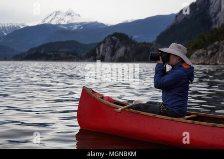 Männliche Fotografen auf ein hölzernes Kanu ist, die Bilder von der schönen kanadischen Bergwelt. In Squamish, nördlich von Vancouver, BC, Kanada Stockfoto