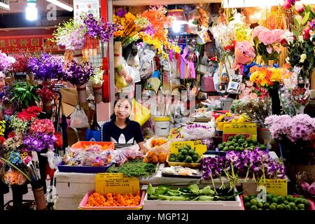 Singapur - 25. April 2018: Chinesische Dame Lagerhalter außerhalb ihrer farbenfrohen Obst und Blumen lächeln in einem Markt in Chinatown Abschaltdruck Stockfoto