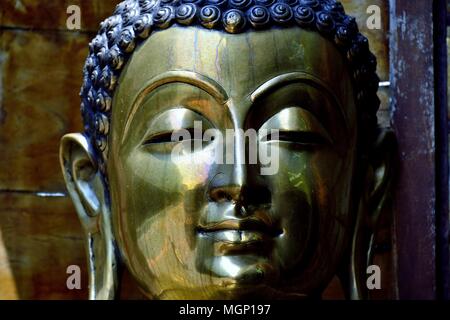 Nahaufnahme von Messing Statue von Buddha zeigt Gesicht mit heiteren Ausdruck und Reiche metallische Farben und Texturen Stockfoto