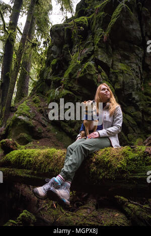 Frau holiding ein kleiner Hund, Chihuahua, in die Arme von wunderschöner Natur umgeben. In Lynn Valley, North Vancouver, British Columbia, Kanada. Stockfoto