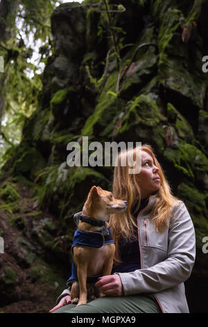 Frau holiding ein kleiner Hund, Chihuahua, in die Arme von wunderschöner Natur umgeben. In Lynn Valley, North Vancouver, British Columbia, Kanada. Stockfoto