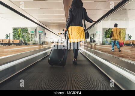 Junge Mädchen Reisenden zu Fuß mit dem Tragen von halten Koffer im Flughafen. Stockfoto