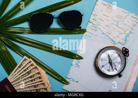 Reisen Vorlage Ansicht von Oben. Weltkarte, Sonnenbrille, Kompass Pass, Dollar, Palmen Blatt auf blauem Hintergrund Stockfoto