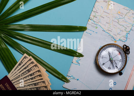 Reisen Vorlage Ansicht von Oben. Weltkarte, Reisepass, Dollar, Kompass, Palmen Blatt auf blauem Hintergrund Stockfoto