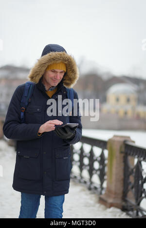 Mann im Winter Kleidung Holding eine Tablette im Freien Stockfoto