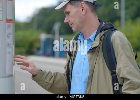 Mann beim Lesen des Fahrplans an einer Bushaltestelle in den Niederlanden Stockfoto