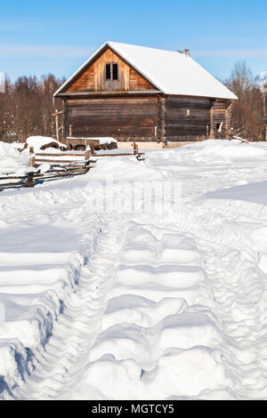 Verschneite Straße im russischen Dorf Kikino in Smolensk in Russland im sonnigen Wintertag Stockfoto