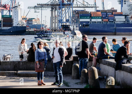 21 April 2018, Deutschland, Hamburg: Menschen genießen Sie die Nachmittagssonne auf einer Struktur für die Elbe an der Elbe Övelgönne Strand. Foto: Markus Scholz/dpa Stockfoto