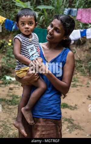 Kandy, Sri Lanka. 15 Feb, 2018. Donnerstag, 15. Februar 2018. MADUSHIKA CHANDRAMALI, ein Unternehmer mit Selbständigkeit Bildung & Welfare Association (SEWA), stellt mit ihrem dreijährigen Sohn außerhalb Ihrer zwei Zimmer Haus in der Nähe von Kandy, Sri Lanka. Sie teilt ihr Haus mit ihrem Mann und zwei Kindern. CHANDRAMALI hat zwei Söhne, 3 und 8 Jahre, mit ihrem Ehemann, der Sie sich an einen Elektriker. Eine ehemalige Textilfabrik Arbeiter, Chandramali hofft, Geld aus ihrer Arbeit mit SEWA zu speichern, um sie nach Hause zu hinzufügen. Sie arbeitet mit SEWA für drei Monate. SEWA ist eine nicht-staatliche Organisation workin Stockfoto