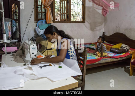 Kandy, Sri Lanka. 15 Feb, 2018. Donnerstag, 15. Februar 2018. MADUSHIKA CHANDRAMALI näht Beutel für Selbständigkeit, Bildung & Welfare Association (SEWA) als ihren dreijährigen Sohn Uhren tv in einem Zimmer ihrer zwei Zimmer Haus, das sie mit ihrem Mann und zwei Kindern in der Nähe von Kandy, Sri Lanka. Chandramali nutzt den Raum wie ein Wohnzimmer, Schlafzimmer, Kinderzimmer, sowie ihre näherei. Sie hat zwei Söhne im Alter von 3 und 8, mit ihrem Ehemann, der Sie sich an einen Elektriker. Eine ehemalige Textilfabrik Arbeiter, Chandramali hofft, Geld aus ihrer Arbeit mit SEWA zu speichern um Zugänge zu ihrem Haus erstellen. Sie hat Stockfoto