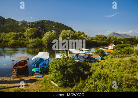 Juni 8th, 2016 - Skutarisee, Montenegro. Fischerboote, Berge und Küste Häuser auf Tsrnoyevicha River in der Nähe von Skadarsko Jezero in Montenegro. Stockfoto