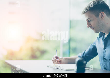 Positives Denken Konzept. Porträt einer stattlichen Geschäftsmann sitzt am Schreibtisch und Schreiben auf Notebook mit Kopie Raum im Bild. Stockfoto