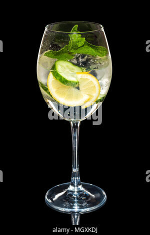Kalte Zitrone und Gurke Cocktail mit Sekt mit Eiswürfel im Wein Glas isoliert auf Schwarz Stockfoto