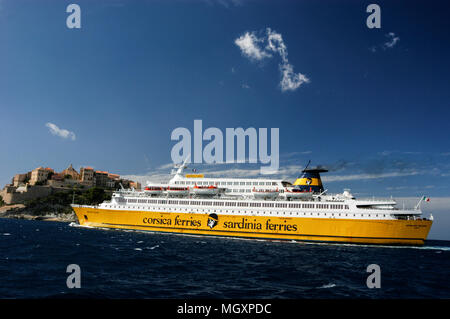 Ein Passagier- und Autofähre, Corsica Ferries und Sardinia Ferries nähert sich der Hafen von Calvi auf Korsika, wie es Segel an der Zitadelle von Calvi entfernt auf einem Hügel. Th Stockfoto