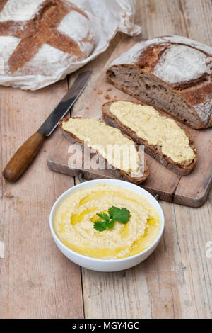Sauerteigbrot und Dinkelsauerteig Brot mit hausgemachtem Hummus auf einem Brotbrett. VEREINIGTES KÖNIGREICH. Stockfoto