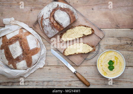 Sauerteigbrot und Dinkelsauerteig Brot mit hausgemachtem Hummus auf einem Brotbrett. VEREINIGTES KÖNIGREICH.