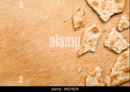 Gebrochene Cracker und Krümel auf Holz- Hintergrund. Stockfoto