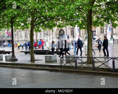 Eine Masse von Touristen, Regenjacken und Schirme, Spaziergang im Regen über die Plaza vor der Hôtel de Ville, Paris, Frankreich. Stockfoto