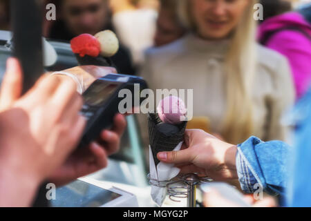 Warteschlange für eine Vielzahl von köstlichen frischen Eis mit einem neuen Geschmack in Schwarz wafer Hörner. Zahlung per Terminal per Kreditkarte. Reale Szene in Th Stockfoto