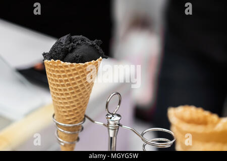 Weiches schwarzes Eis in traditionellen portioniert Waffel Kegel serviert auf stehen. Trendy essen. Beliebte Köstlichkeiten für Erwachsene und Kinder. Selektive konzentrieren. R Stockfoto