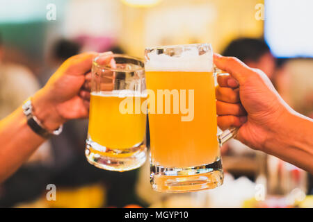 Freunde oder Kollegen jubeln mit Bier, gemeinsam Feiern im Restaurant und Nachtclub. Junge Menschen toasten bei Party Event nach der Arbeit Stockfoto