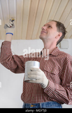 Auftragnehmer lackieren Holzpaneele an der Decke Stockfoto