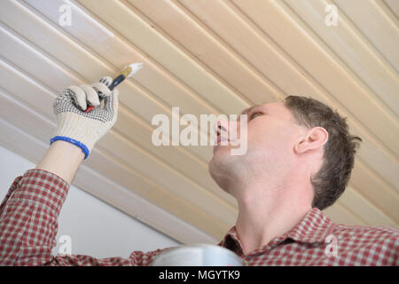 Auftragnehmer lackieren Holzpaneele an der Decke Stockfoto