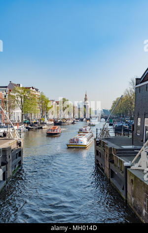 Sightseeing Boote verlassen ein Schloss an einer Gracht in Amsterdam. Als das Venedig des Nordens bekannt, Amsterdam verfügt über mehr als 100 Kilometer Kanäle. Die netherl Stockfoto