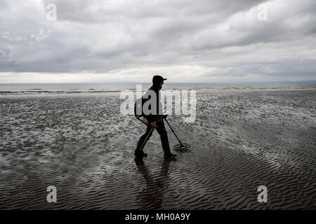 Ein Mann mit einem Metalldetektor auf Barry Island Beach, Wales. Stockfoto