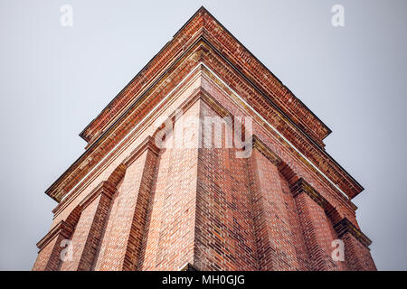 Hoher Turm mit roten Ziegeln von unten auf einem grauen und blauen Hintergrund Stockfoto