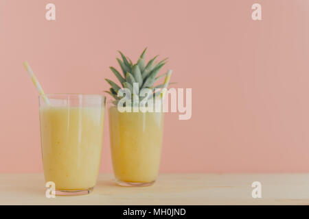 Zwei Gläser gefüllt mit frischen Ananas Smoothie und mit bunten Strohhalmen serviert. Stockfoto