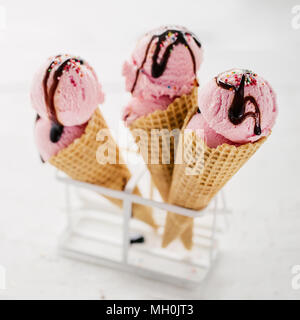 Paar Waffeln gefüllt mit rosa Eis serviert mit Schokolade topping und Streuseln. Stockfoto