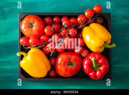 Sortierte Tomaten und Paprika in Holzkiste Stockfoto