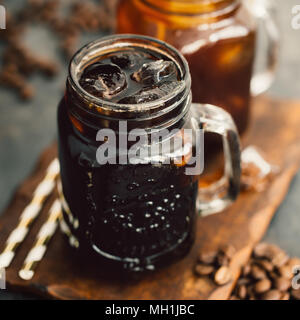 Zwei Gläser mit verschiedenen dunklen erfrischende Getränke auf Holzbrett serviert. Stockfoto