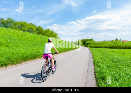 Junge Frau Radfahren auf die ländliche Straße entlang der Weichsel in der Nähe von Krakow City während der Saison Frühjahr, Polen Stockfoto