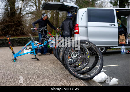 Zwei Männer Mountainbikes von einem Mercedes Vito Van auf einem Parkplatz auspacken an Grizedale im Lake District. Stockfoto