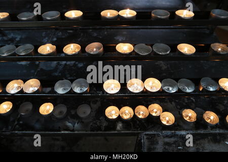 Brennende Kerzen in der Kirche. Begriff der Religion. Heiliges Licht, dunklen Hintergrund. Helles gelbes Licht am Abend, close-up. Viele brennende Kerzen in c Stockfoto