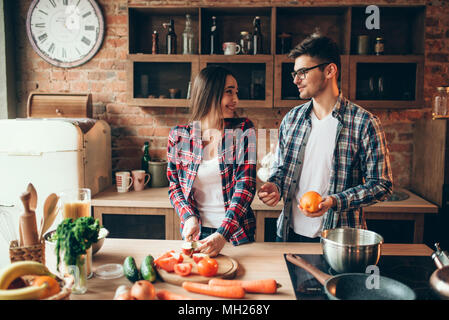 Mann jongliert Orangen, während Frau kochen Stockfoto