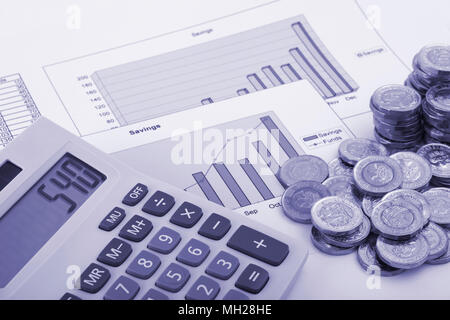 Ein Rechner sitzen auf einige Grafiken beschriftet Einsparungen und Mittel mit einigen neuen (Post 2016) Pound Münzen. Stockfoto